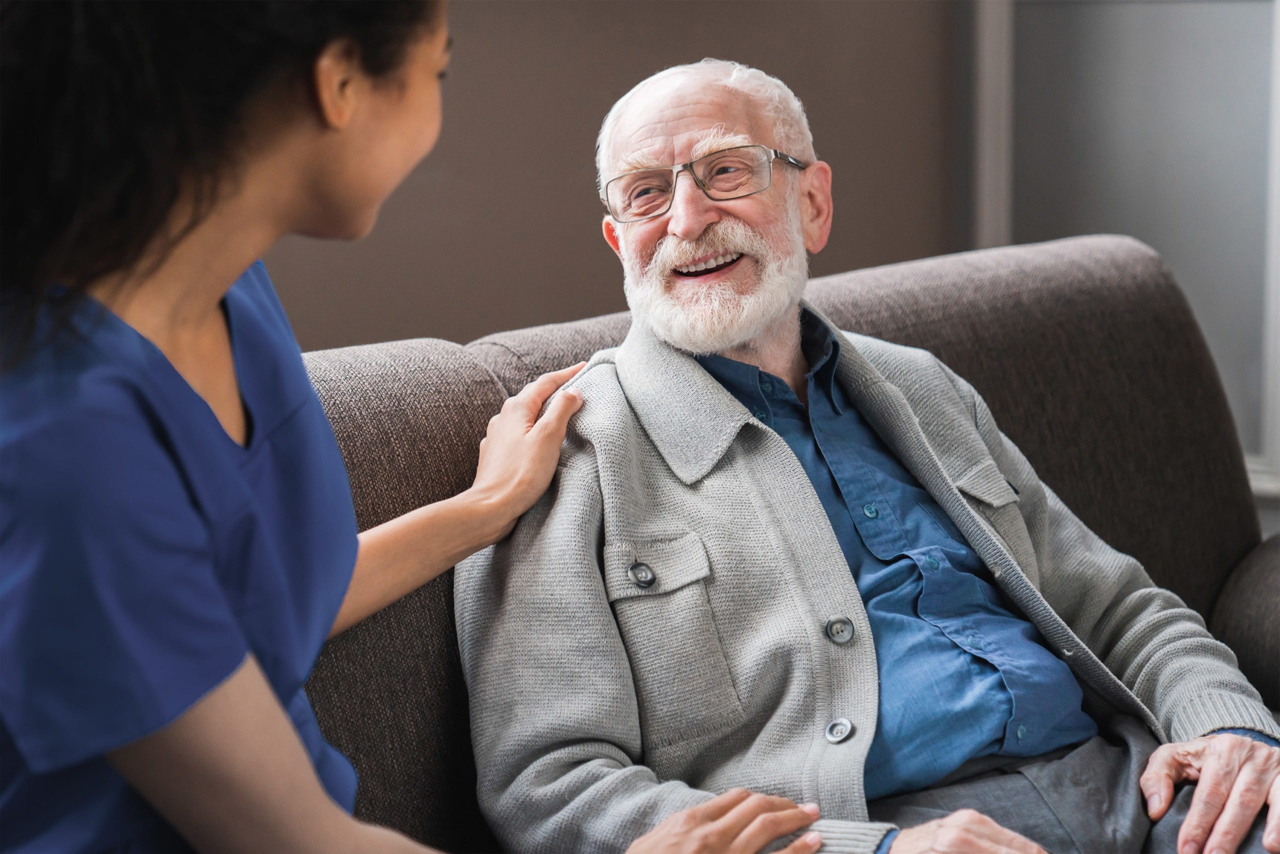 Smiling elderly man sat chatting with a carer.